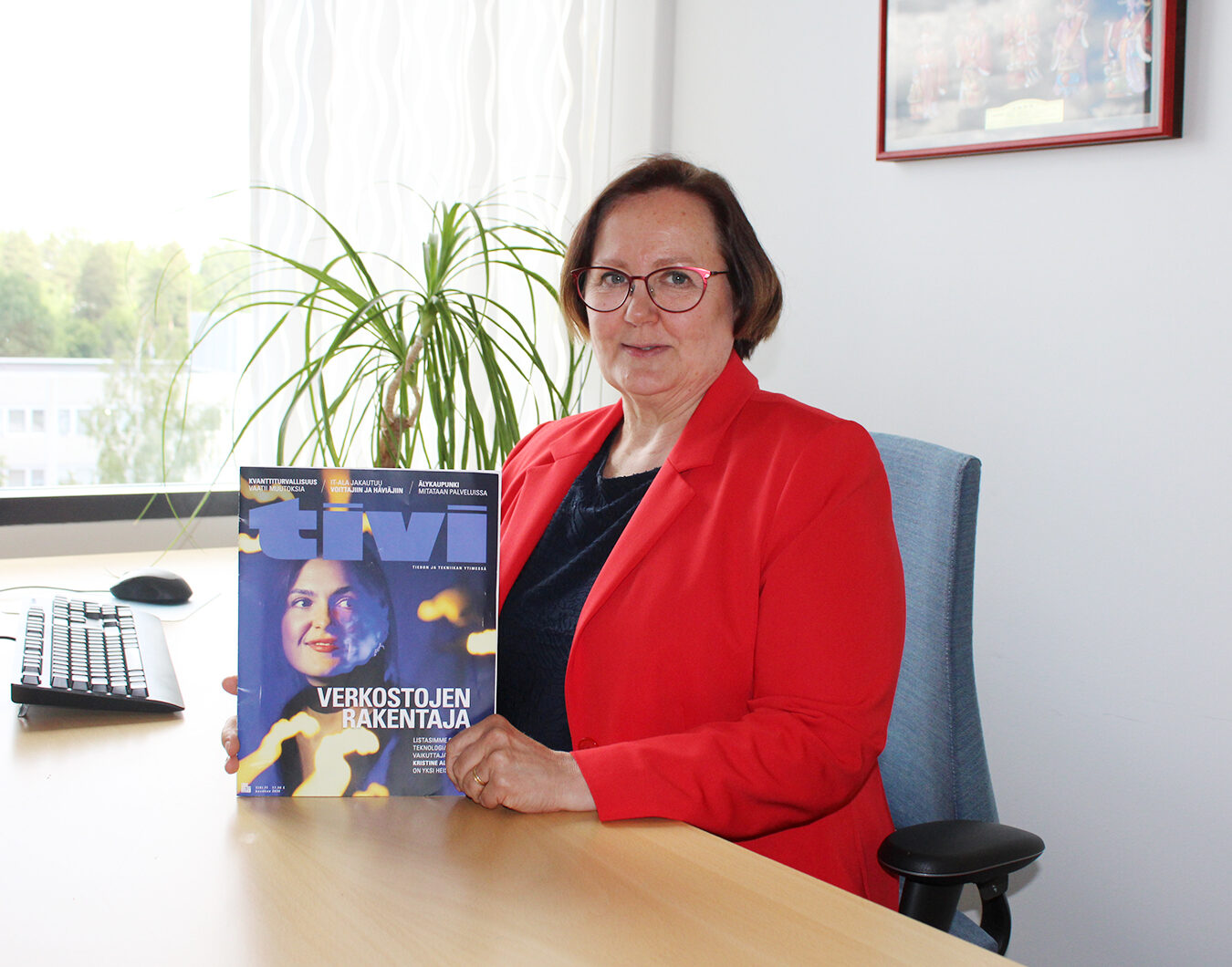 Anna-Riikka Vuorikari-Antikainen sitting by her desk, holding a TiVi magazine